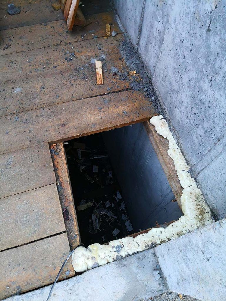 Jak nie powinno wyglądać BHP na budowie. Na zdjęciu widać głęboką dziurę w drewnianej podłodze, która nie jest zabezpieczona.